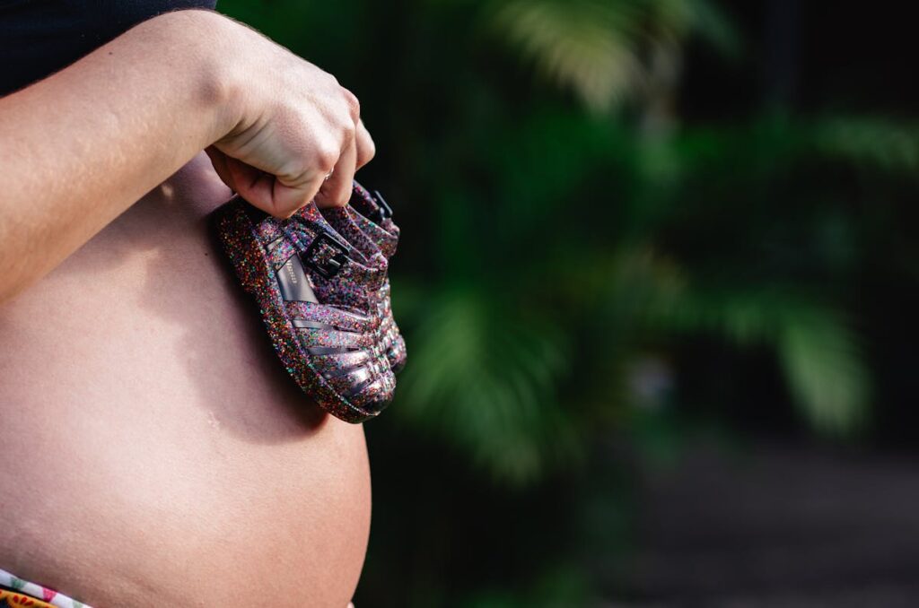 Pregnant Woman Holding Baby Shoes on her Belly