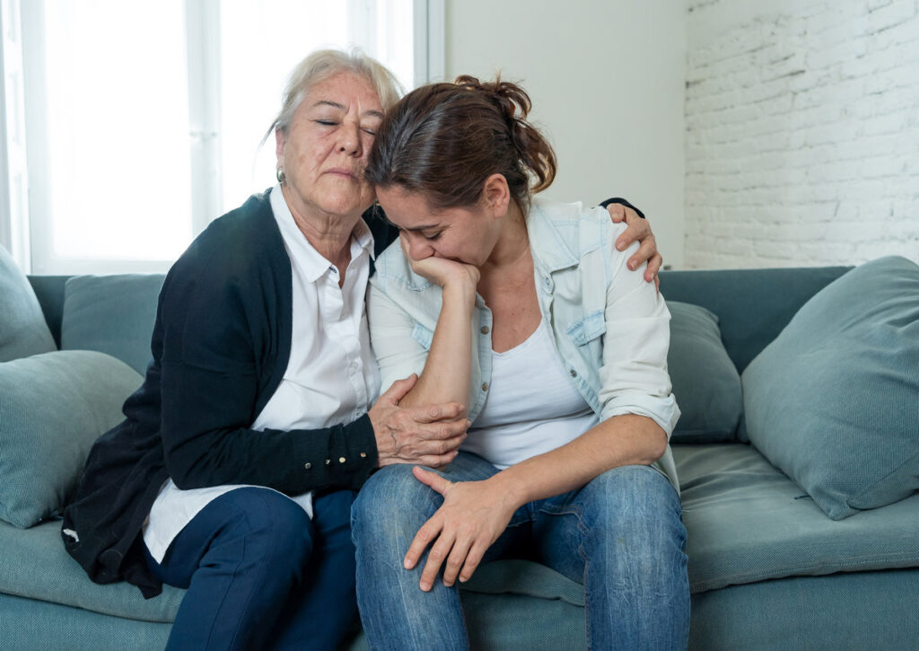 Senior mother comforting adult daughter grieving loss of loved one.
